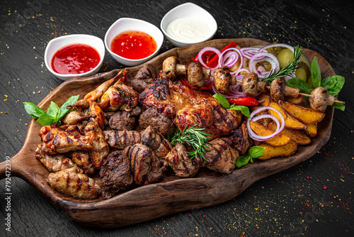 Meat set for a large group. A dish of different types of meat: beef steak, pork cuts and ribs, chicken kebab and grilled quail, lamb ribs. Menu for a pub on a dark background.