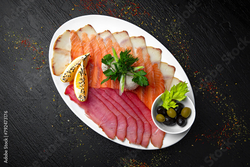 Slicing delicately salted fish: tuna, salmon and butter fish. Menu for a pub on a dark background. Colorful juicy food photography. photo