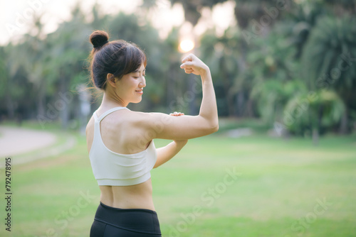 Strong fitness asian woman runner showing off muscular arms flexing biceps. wellbeing success concept.