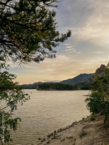 Calm lake Borovoe with a rocky shore and distant mountains at sunset photo