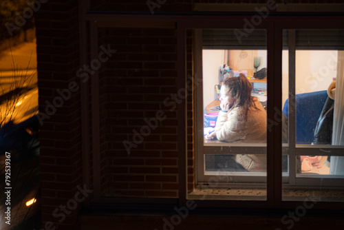 persona estudiando vista en una noche  obscura desde la ventana