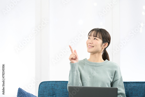 ノートパソコンを操作しながら指差しをする女性
