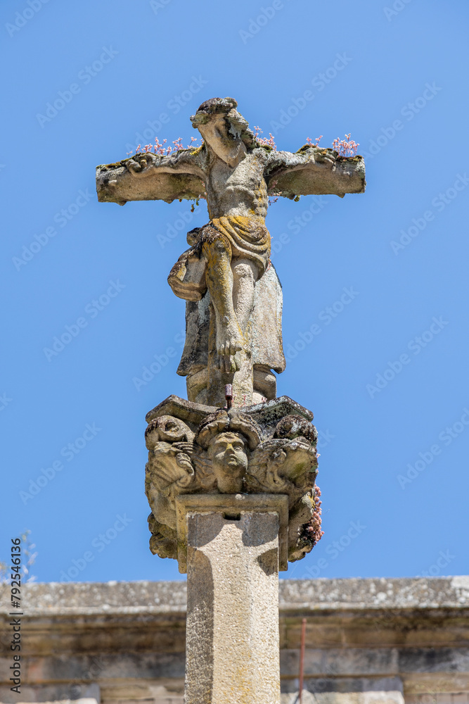 A close-up of a weathered Jesus Christ statue on a cross with intricate details and sky in the background, capturing the essence of faith and history