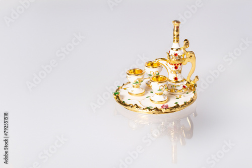 Elegant white and gold tea set displayed on a white plate on white background. Copy space