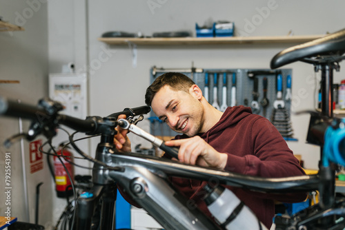 Smiling bike mechanic while manipulating the handlebar of an electric mountain bike with a ratchet wrench.