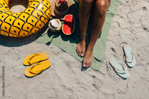 Sunbathe at the beach Women's feet, sandals and fruit