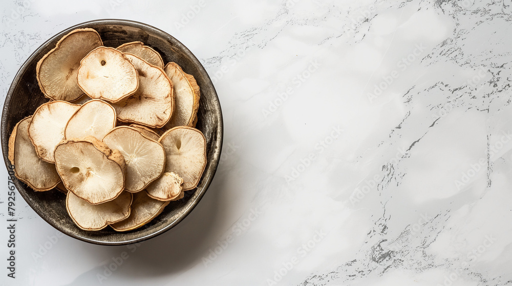 Taro slices in a bowl on a white table, top view, space on the right Taro slices in a bowl on a white table, top view, space on the right