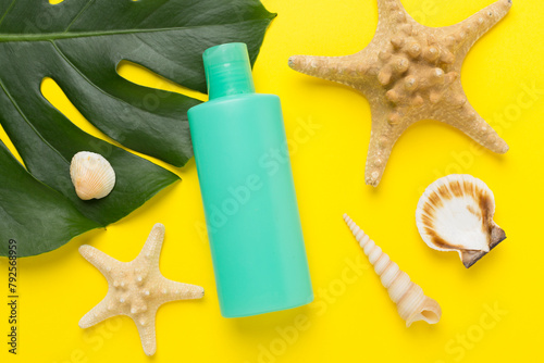 Sunscreen lotion with summer decor on color background, top view