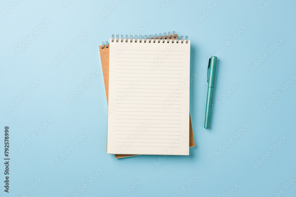 Top view of notebook and fountain pen on blue background