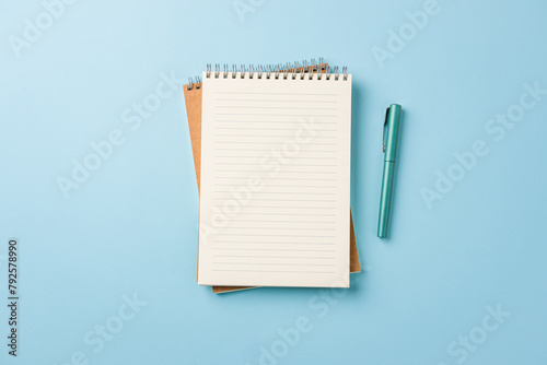 Top view of notebook and fountain pen on blue background
