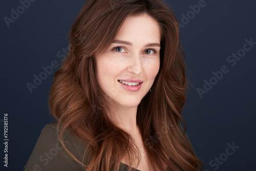 A close-up portrait of a beautiful young woman with pearly white teeth and green eyes looking directly into the camera