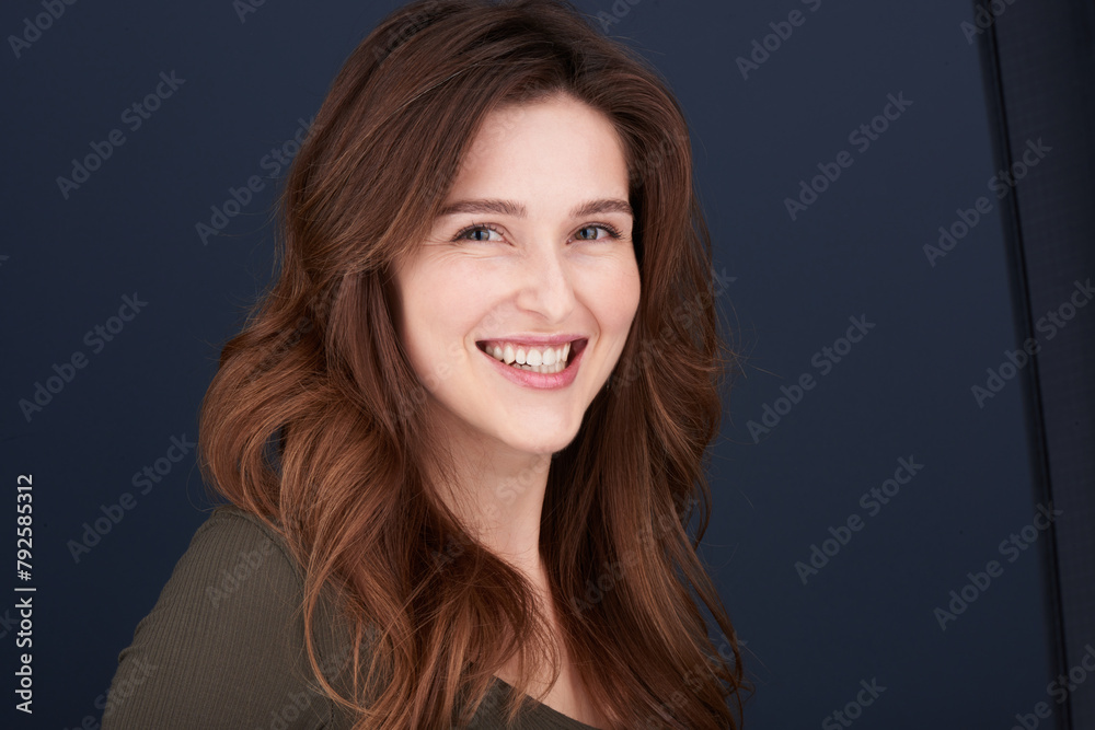 A close-up portrait of a beautiful young woman with pearly white teeth and green eyes looking directly into the camera with a lovely smile