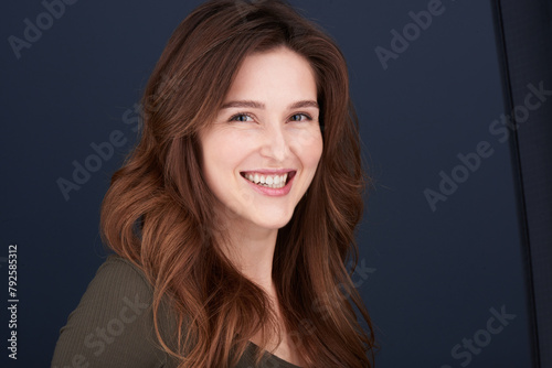 A close-up portrait of a beautiful young woman with pearly white teeth and green eyes looking directly into the camera with a lovely smile