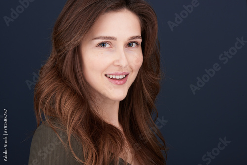 A close-up portrait of a beautiful young woman with pearly white teeth and green eyes looking directly into the camera with a lovely smile