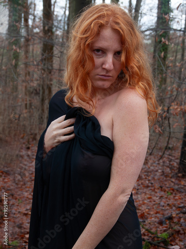 Portrait of a sexy young redhead red-haired annoyed woman covered with a black scarf