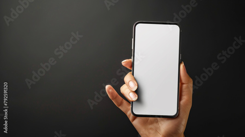 A hand displaying a blank smartphone screen mockup in a direct view over a black backdrop -  photo