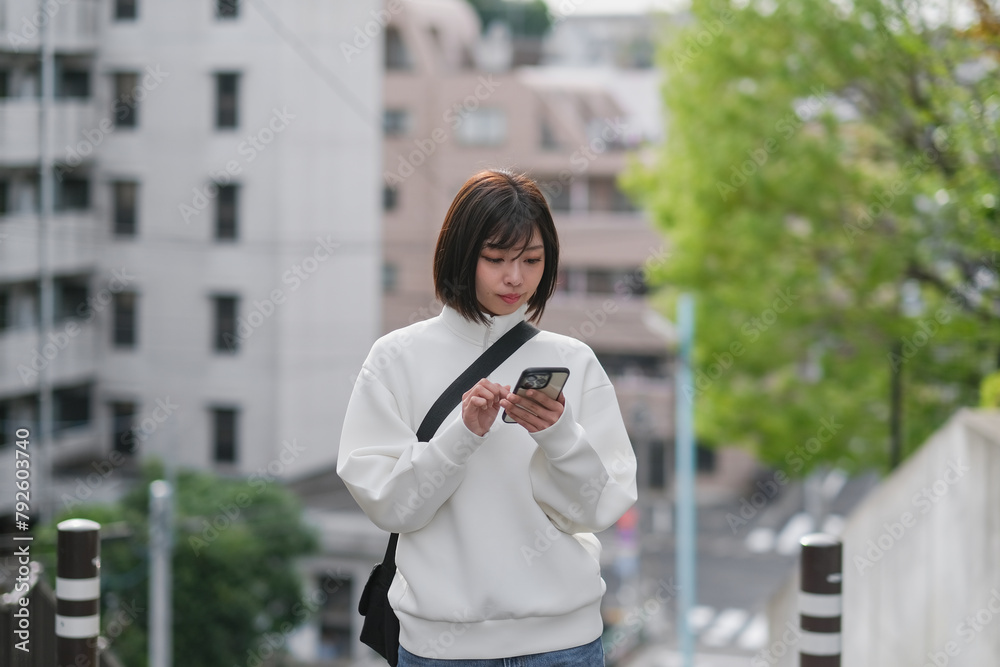 Fototapeta premium 坂の上でスマートフォンを見る女性