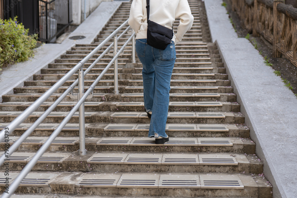 住宅街の坂道を上る女性のうしろ姿