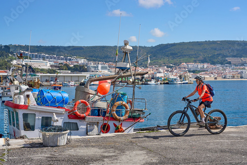 nice senior woman cycling with her electric mountain bike on the fishermens jetty of Sesimbra, Portugal photo