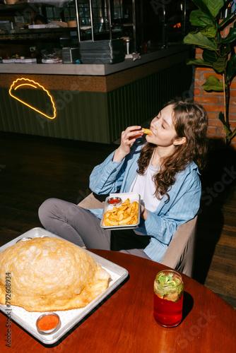 Woman enjoying big cheburek with potato dips and berry mojito photo