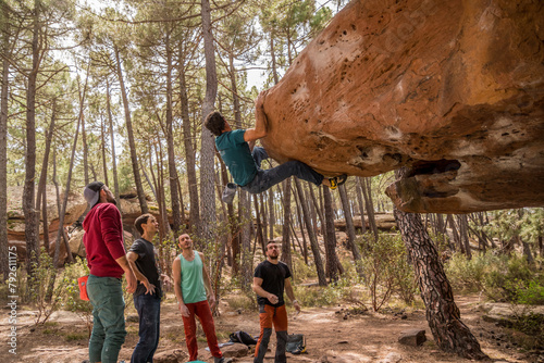 Group of friends practicing bouldering in the pine forest of Albarracin.