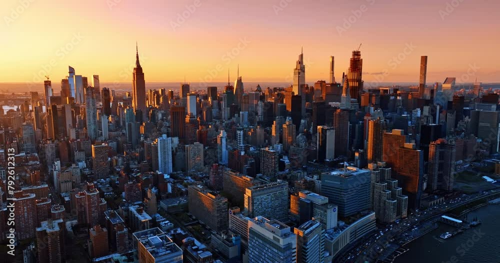Splendid skyscrapers lit with orange light of setting sun. Metropolis panorama from drone footage.
