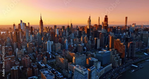 Splendid skyscrapers lit with orange light of setting sun. Metropolis panorama from drone footage.