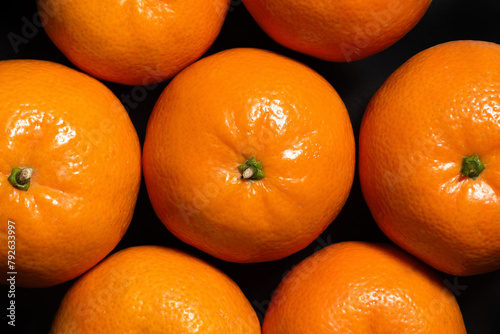 Fresh tangerines on a black background, top view. Food background
