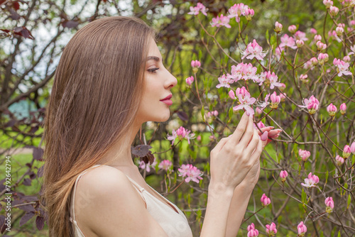 Brunette fashion model with long brown hair and natural makeup against floral background outdoor © artmim