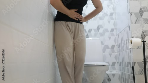 Woman Experiencing Stomach Pain in a Modern Home Bathroom Setting