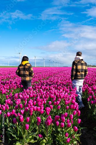 Two people standing joyfully in a field of vibrant purple tulips, surrounded by the beauty of Spring in the Netherlands photo