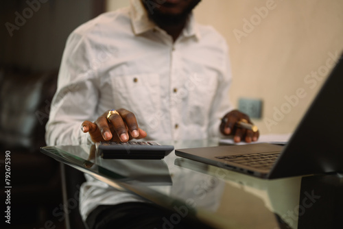 Cropped shot of African man calculating expenses and managing personal budget
