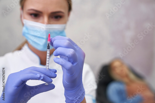 Doctor preparing syringe before beauty procedure