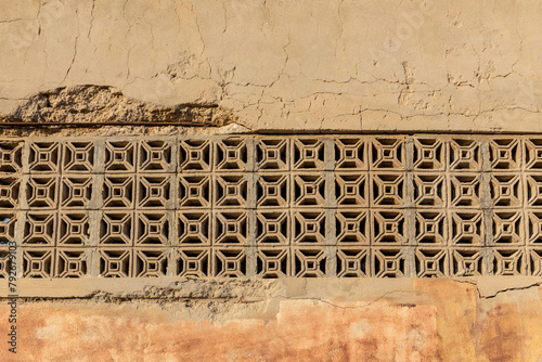 Old stone wall with openwork arabic ornaments in Al Jazirah Al Hamra haunted town in Ras Al Khaimah, UAE, close-up view.