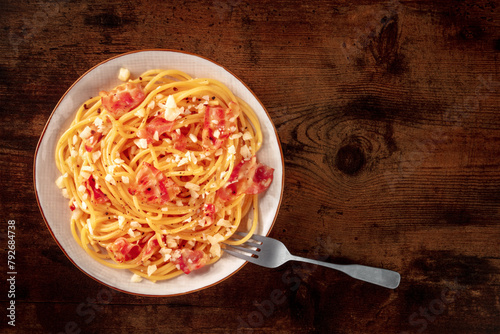 Carbonara pasta dish, traditional Italian spaghetti with pancetta and cheese, overhead flat lay shot with a fork and copy space, on a rustic background