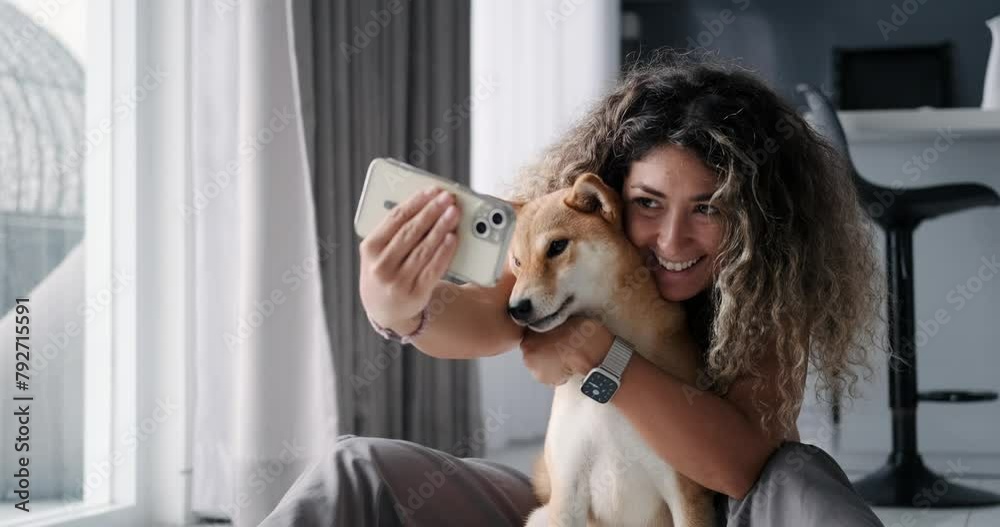 A young woman with curly hair takes a selfie with her Shiba Inu dog ...