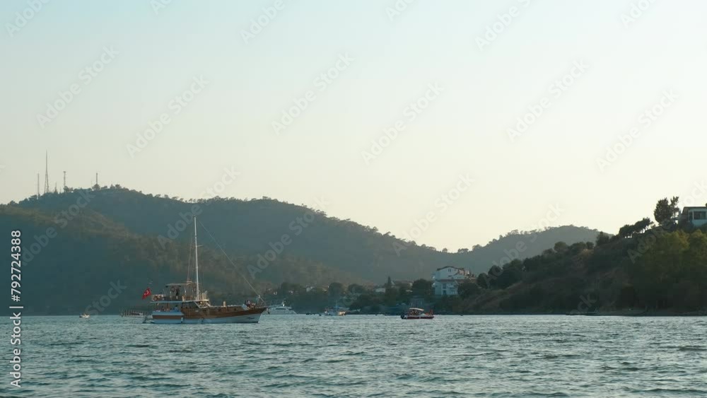 Sailing ship by abandoned mountains. A view of sailing old yacht with travelers by the abandoned coast during morning time. Sailing ship by abandoned mountains. A view of sailing old yacht with travelers by the abandoned coast during morning time.