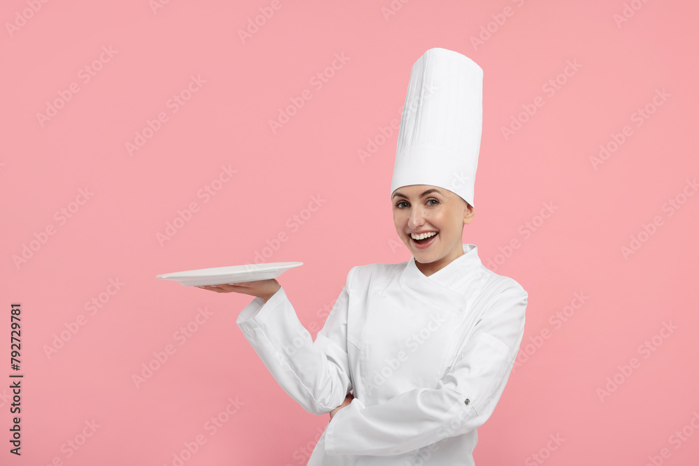 Happy professional confectioner in uniform holding empty plate on pink background Happy professional confectioner in uniform holding empty plate on pink background