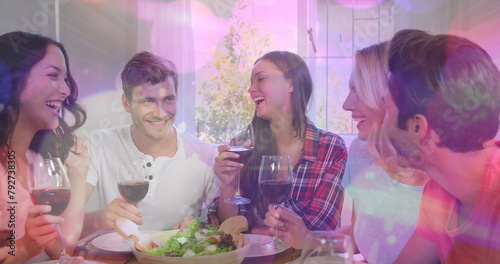 Image of bokeh over happy caucasian female and male friends drinking wine and talking