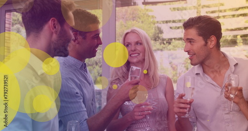 Image of yellow dots over happy caucasian female and male friends drinking wine and talking