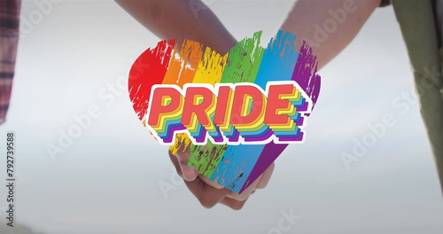 Image of rainbow heart and pride over hands of caucasian lesbian couple