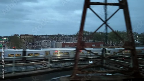 A shot of a Long Island railroad train traveling on a cloudy day. The camera truck right on one train running through a neighborhood in Queens, New York in the other direction. photo