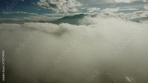 Aerial view of Pasochoa volcano shrouded in thick white fog on a sunny day. View over Machachi City, Pichicnha province, Ecuador