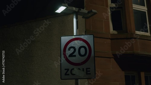 Flashing street light witj 20 Zone road sign - twenty mph UK speed limit, late night shot. Faulty lamp photo
