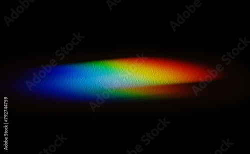 Rainbow reflective colorful sunlight on textured surface of wall. Dispersion and refraction of light.