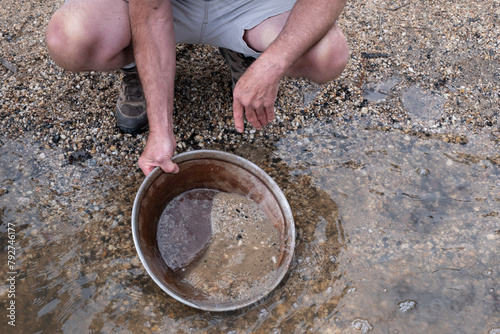 Searching for gold with an iron pan in a riverbed. Gold panning