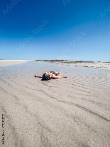 Young Girl laying in tide pool  at Low Tide on Cape Cod beach photo