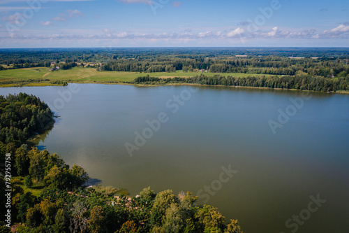 Valmiera, Latvia - August 10, 2023 - Aerial view of a large lake surrounded by forests and fields on a clear day.