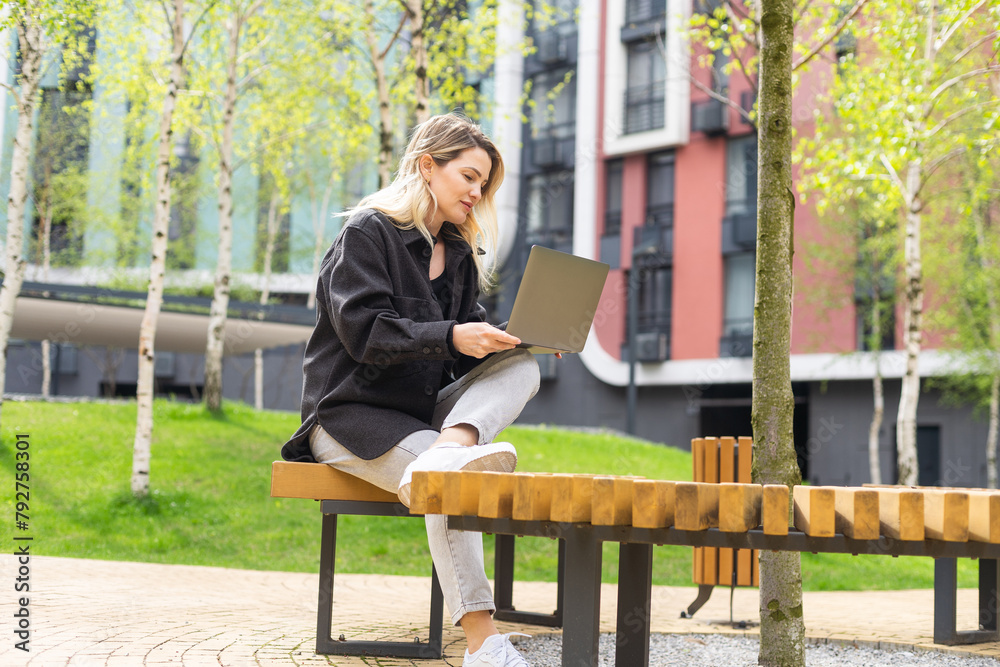 Fototapeta premium Young woman with laptop outside