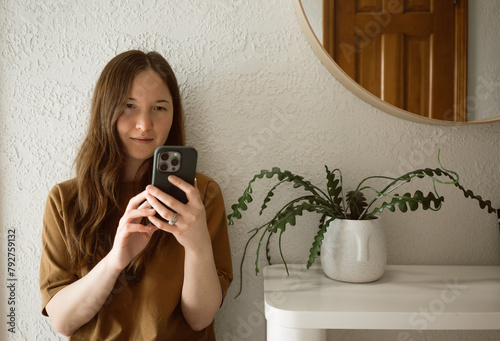 Woman scrolls on phone while sitting in minimal interior space